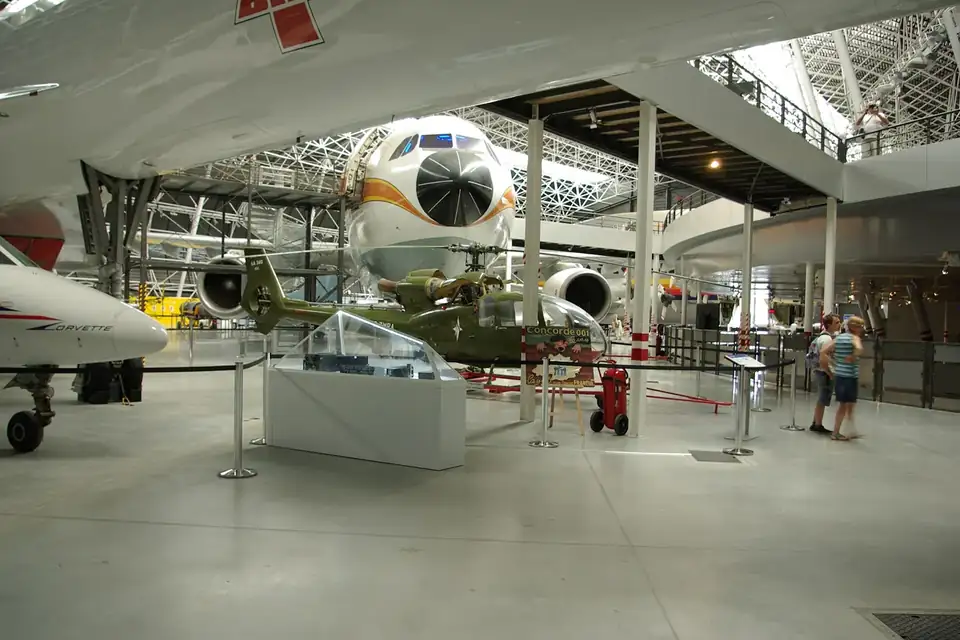 Le grand hall d'un musée aéronautique, avec un avion supersonique exposé au-dessus des visiteurs