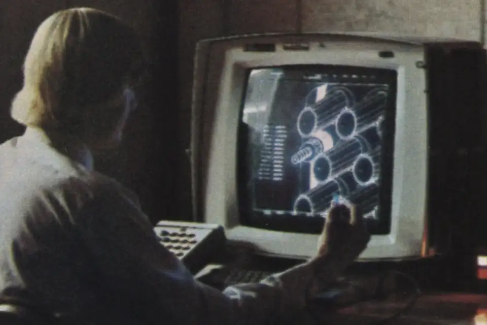 Une ingénieure travaille sur un poste de conception assistée par ordinateur ancien, avec un stylet optique devant l'écran