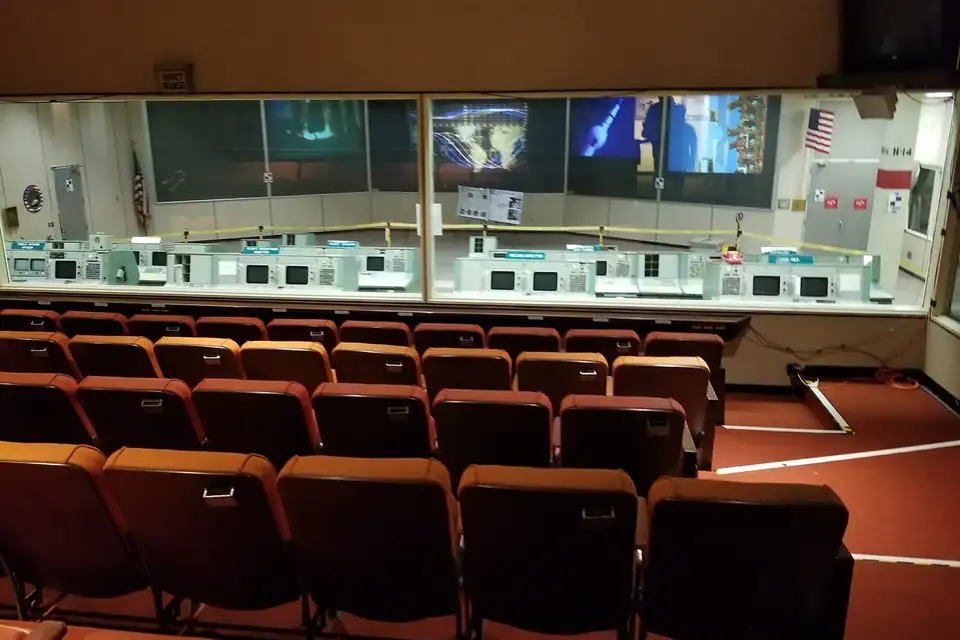 Une salle de contrôle avec des pupitres et de grands écrans muraux affichant des données